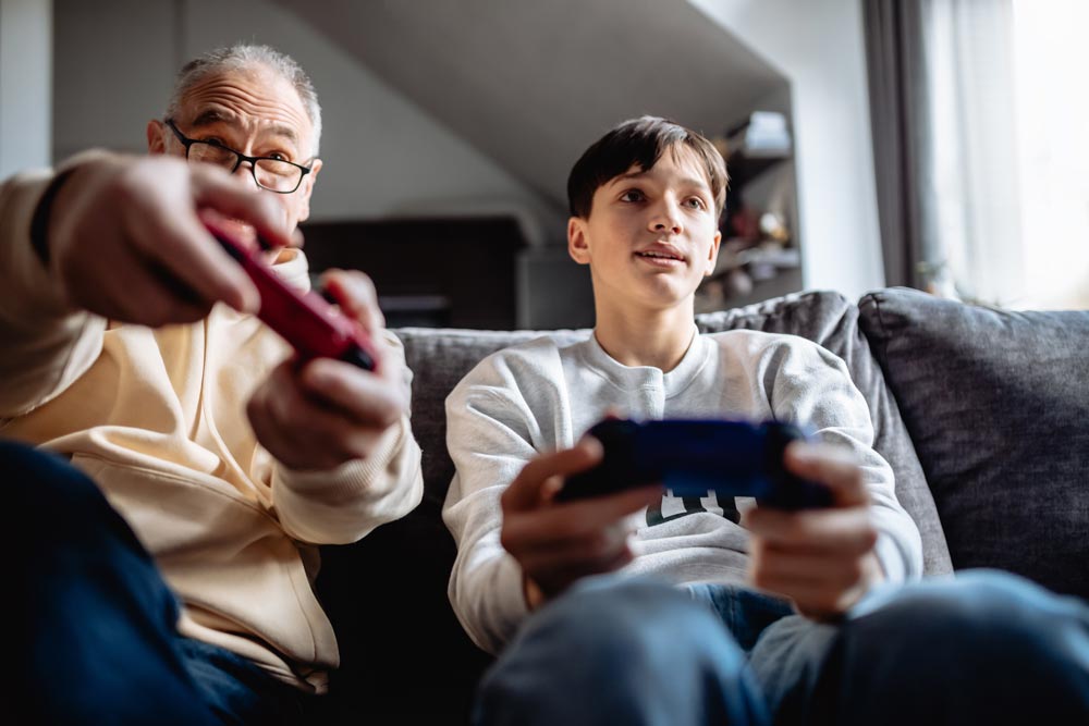 Familjehemsförälder spelar ett spel tillsammans med en tonårspojke i en soffa
